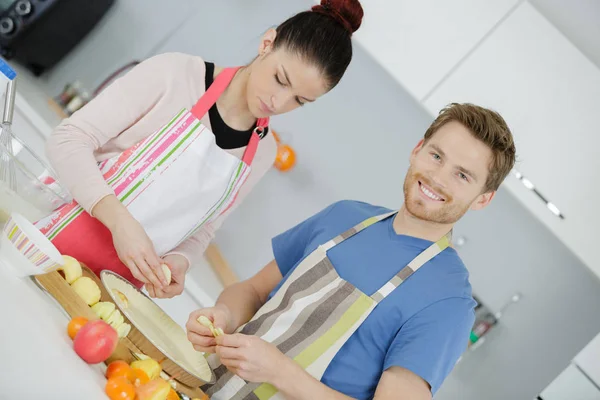 Sonriente pareja joven cocinando comida en la cocina —  Fotos de Stock