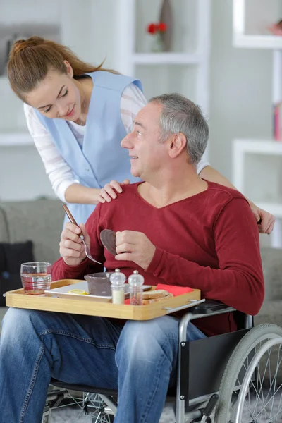 Jeune belle infirmière aidant homme âgé handicapé à la maison — Photo