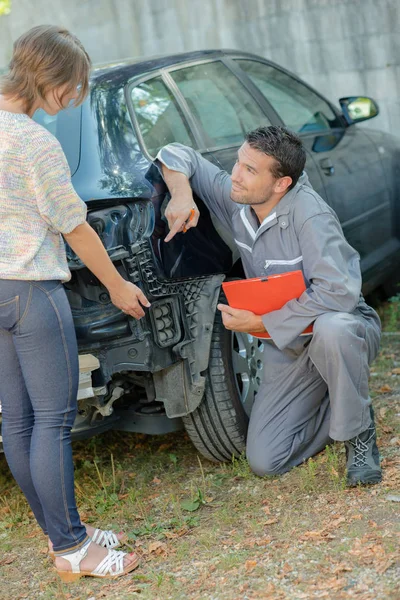 Mécanicien pointant vers les dommages à l'arrière de la voiture — Photo