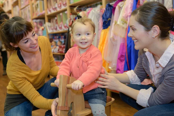 Moeder en dochter met aantrekkelijke leverancier in de speelgoedwinkel — Stockfoto
