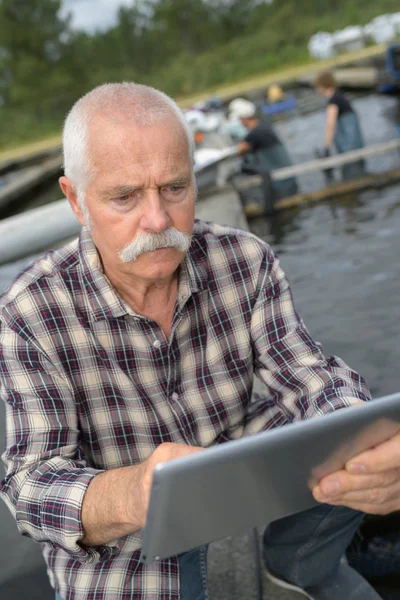 タブレットを使用して漁業で年配の男性 — ストック写真