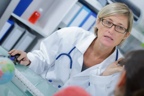 Женщина-врач в разговоре с пациентом в медицинском кабинете — стоковое фото