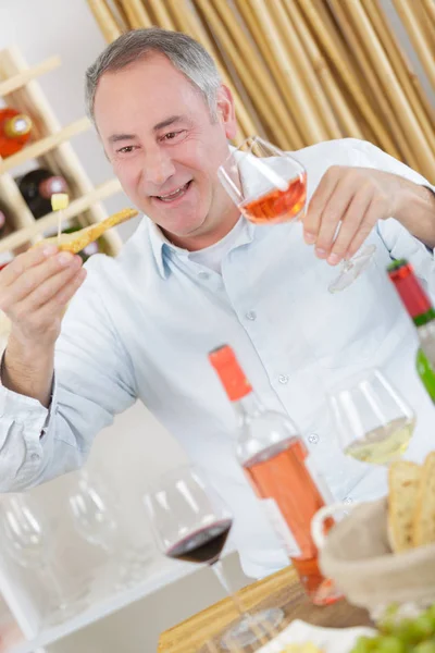 Schöner reifer Mann, der ein Glas Rosenwein probiert — Stockfoto