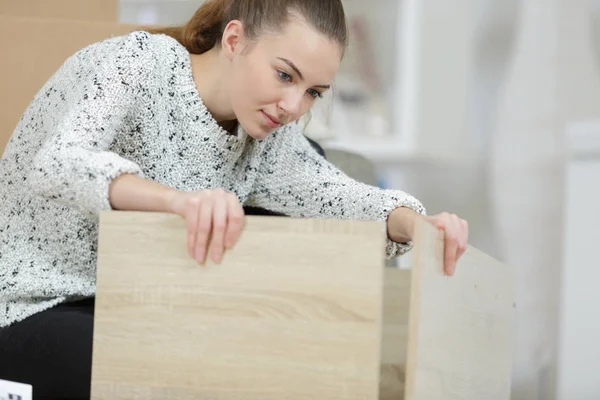 Mulher montando móveis em casa no chão — Fotografia de Stock