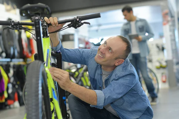 Hombre eligiendo una bicicleta en la tienda de bicicletas —  Fotos de Stock