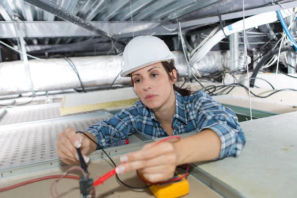 Female electrician calibrating ceiling lamps — Stock Photo, Image