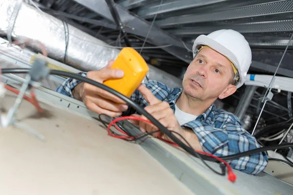 Elektricien inspectie van de dode draden op de top van het plafond — Stockfoto