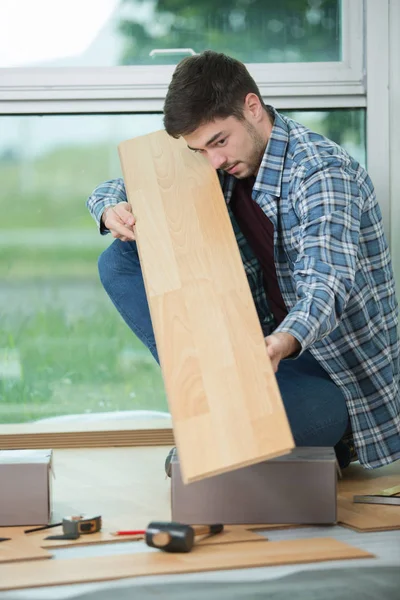 Молодий чоловік тримає дерев'яну підлогу — стокове фото