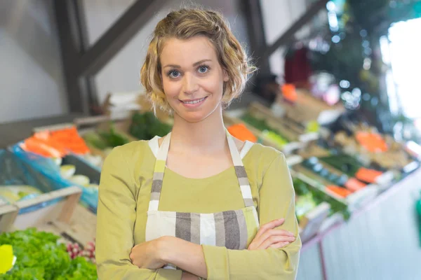 Porträt einer lächelnden Frau in Schürze, die Gemüse verkauft — Stockfoto