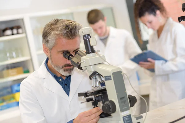 Closeup zralé muže vědec pomocí mikroskopu v laboratoři — Stock fotografie