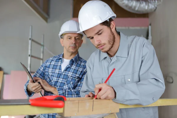 Junge Industrieschreinerin markiert den Holzbalken — Stockfoto