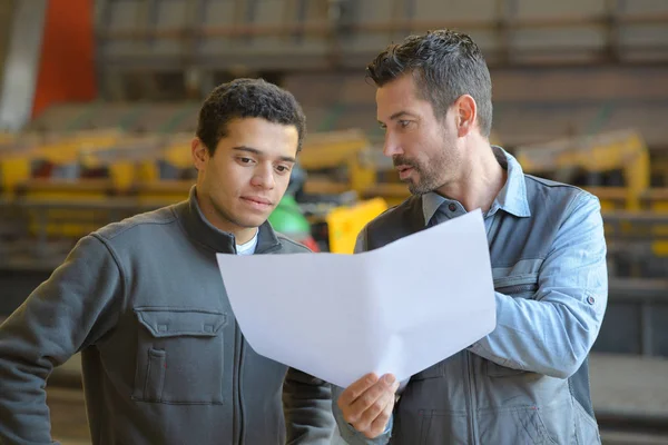 Man hålla pappersarbete och att ge instruktioner till Juniorsvit arbetare — Stockfoto