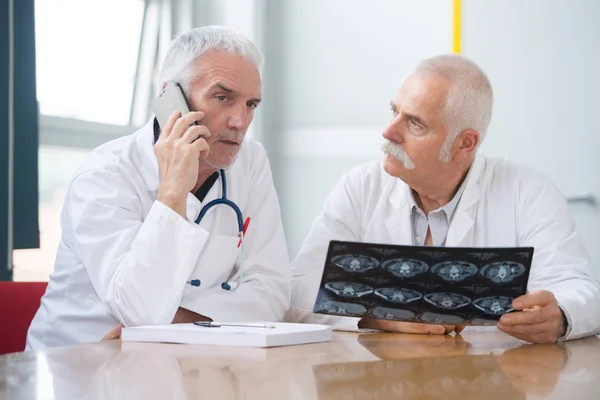 Dos consultores senior con rayos X, uno hablando por teléfono — Foto de Stock