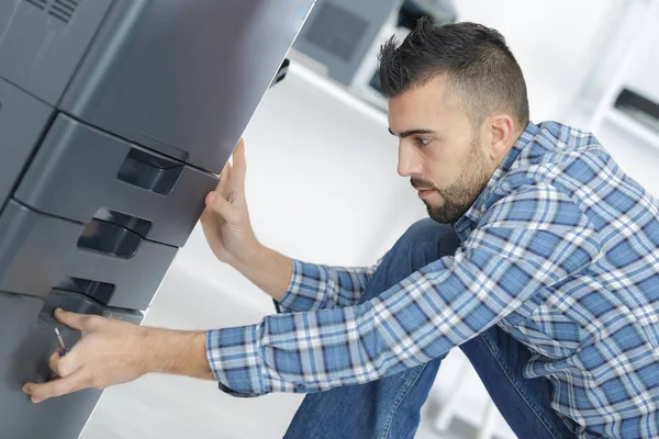 Людина фіксує картридж в принтерній машині в офісі — стокове фото