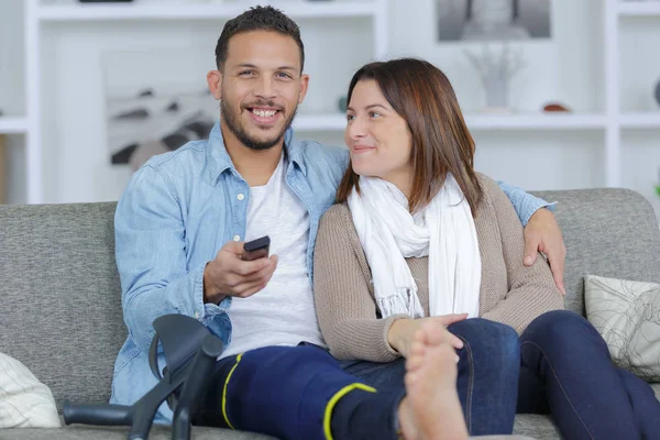 Yaralı erkek ve kız arkadaşı, evde tv izlerken — Stok fotoğraf