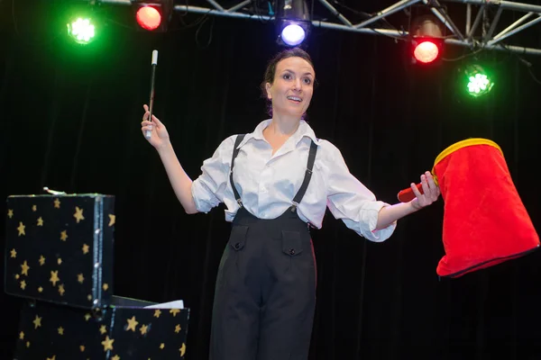 Happy female magician doing a trick in a stage — Stock Photo, Image