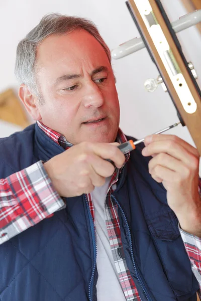Middle-age man fixing the door with screwdriver — Stock Photo, Image