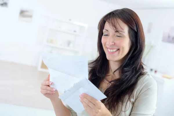 Mujer sonriendo mientras lee una carta — Foto de Stock