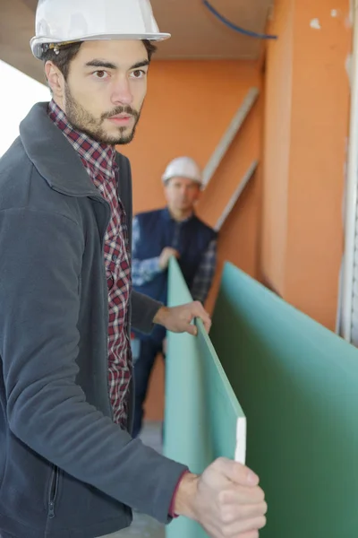 Byggare som transporterar träskivor inomhus — Stockfoto