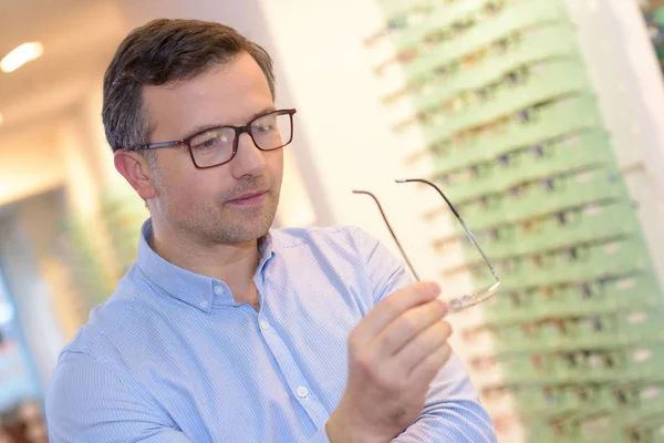Optiker visar glasögon till människan på optik butik — Stockfoto