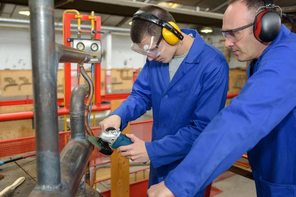 Trabajadores masculinos en ropa protectora sosteniendo protectores de oídos en fábrica —  Fotos de Stock