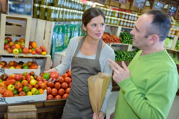 Asistente de tienda que sirve tomates al cliente masculino —  Fotos de Stock