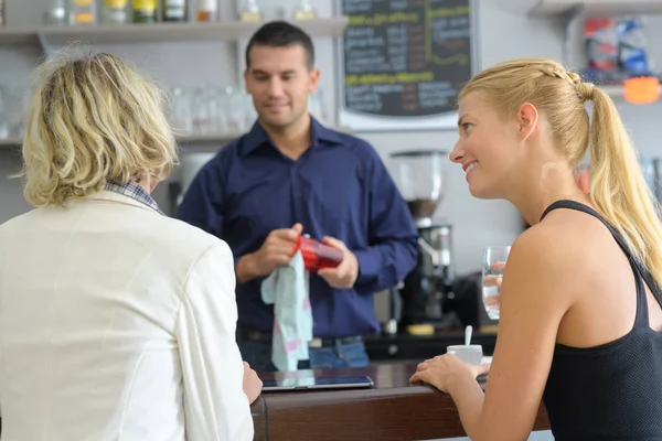 Jovens clientes felizes e barista masculino no café — Fotografia de Stock