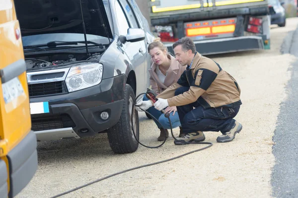 Mecânico masculino inflando um pneu de carro perto de seu cliente feminino — Fotografia de Stock