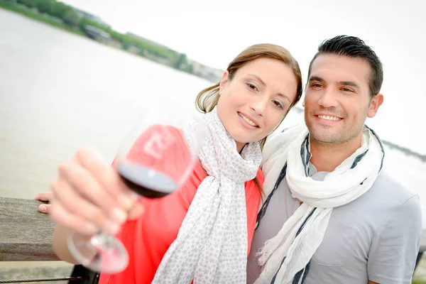 Pareja bebiendo vino junto al río — Foto de Stock