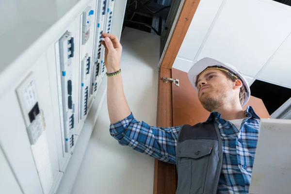 Joven electricista trabajando en panel eléctrico —  Fotos de Stock