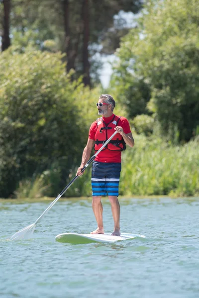 Man enjoying a ride on the lake with paddleboard — Stock Photo, Image