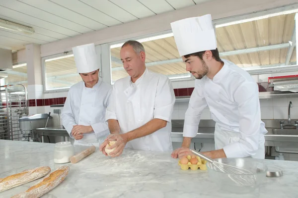 Boulanger et assistants dans la cuisine de la boulangerie — Photo