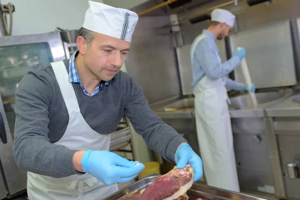 Lehrling und Chef bereitet in Restaurantküche Fleisch zu — Stockfoto