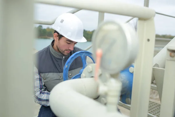 Man turning wheel on pipework — Stock Photo, Image