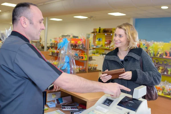 Glimlachend jonge mannelijke winkel bediende portie inkoper bij kassa — Stockfoto