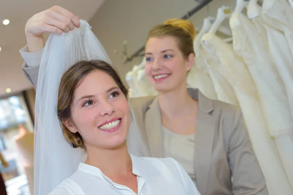 Bride-to-be trying on veils in wedding dress shop Stock Image