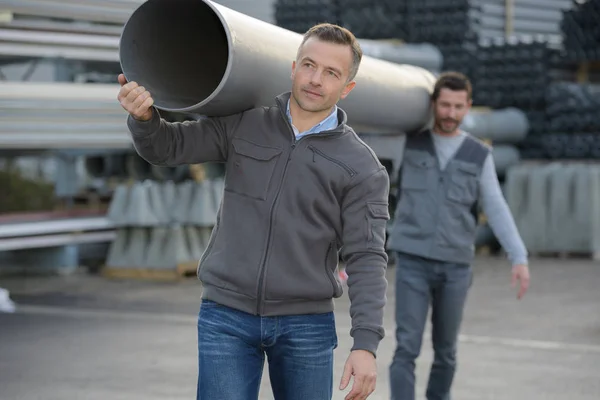 2 workers carrying pipe at factory warehouse — Stock Photo, Image