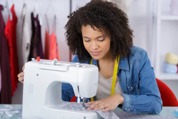 Joven costurera atractiva en el estudio trabajando con la máquina de coser —  Fotos de Stock