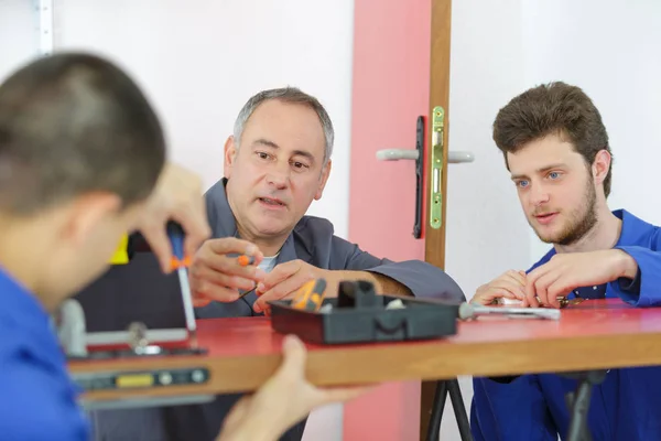 Teacher with students in carpentry class fitting door lock — Stock Photo, Image