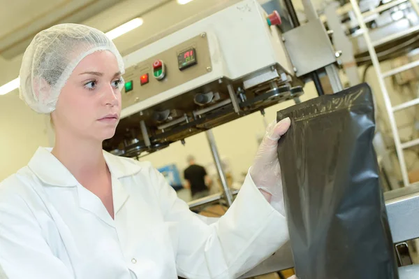 Ouvrière d'usine tenant un sac scellé noir — Photo