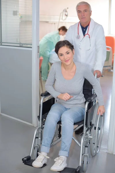 Médecin poussant le patient en fauteuil roulant — Photo