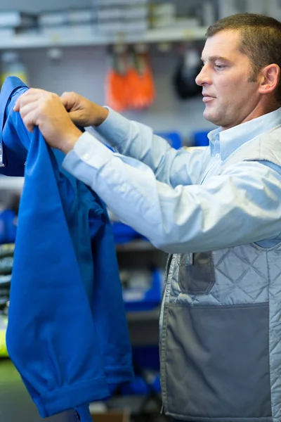 Arbeiter zieht blauen Mantel an, bevor er zur Arbeit geht — Stockfoto