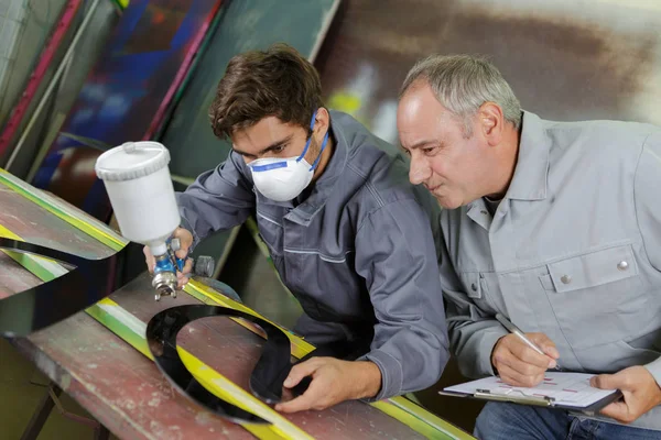 Qualificato giovane fabbrica di lavoro spruzzatura su acciaio — Foto Stock