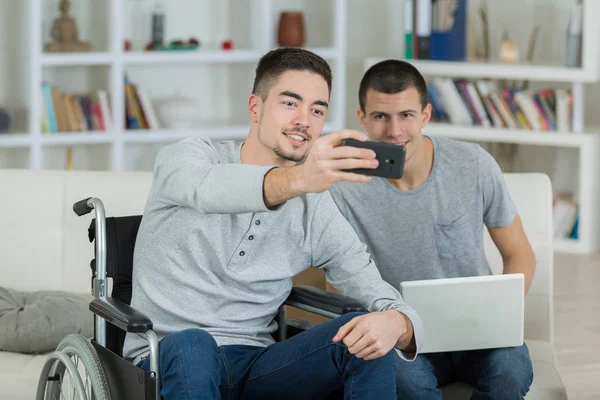 Junger Mann im Rollstuhl macht Selfie mit Freund — Stockfoto