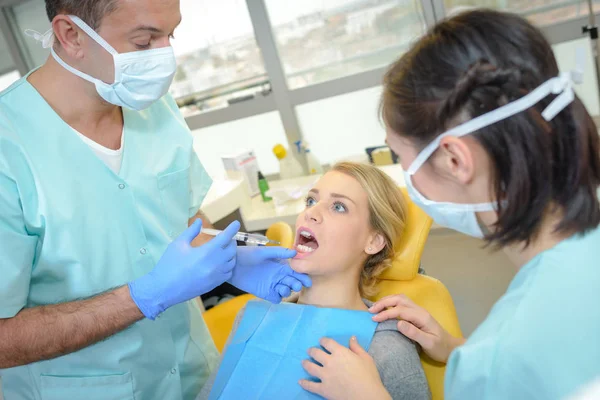 Dentista curando a una paciente en el consultorio dental — Foto de Stock