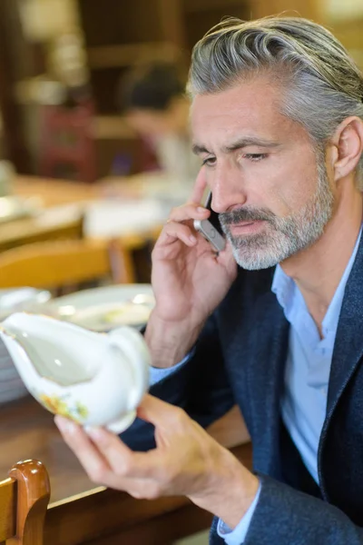Man selecting porcelain item and calling his wife — Stock Photo, Image