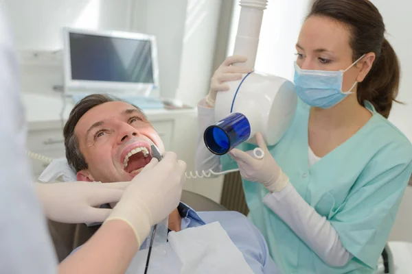 Dentista donna che controlla i denti dei pazienti maschi — Foto Stock