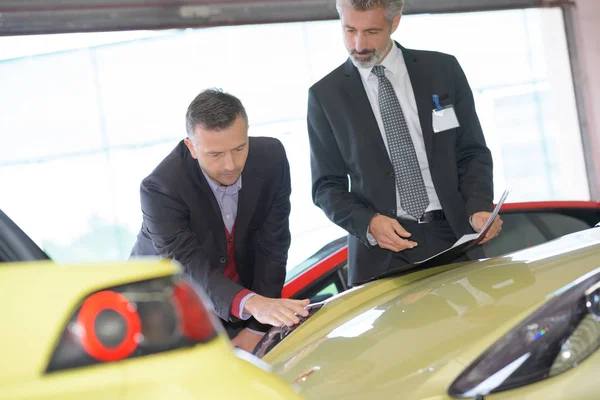 Businessman about to buy a race car at car dealer — Stock Photo, Image