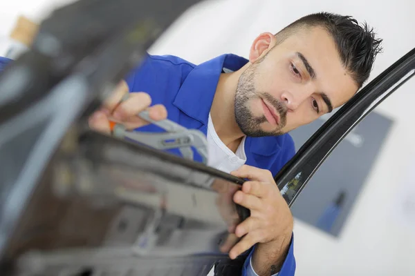 Jovem coachbuilder mecânico endireitando porta do carro — Fotografia de Stock