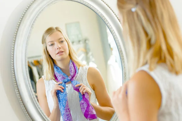 Försöker en halsduk på i en spegel — Stockfoto